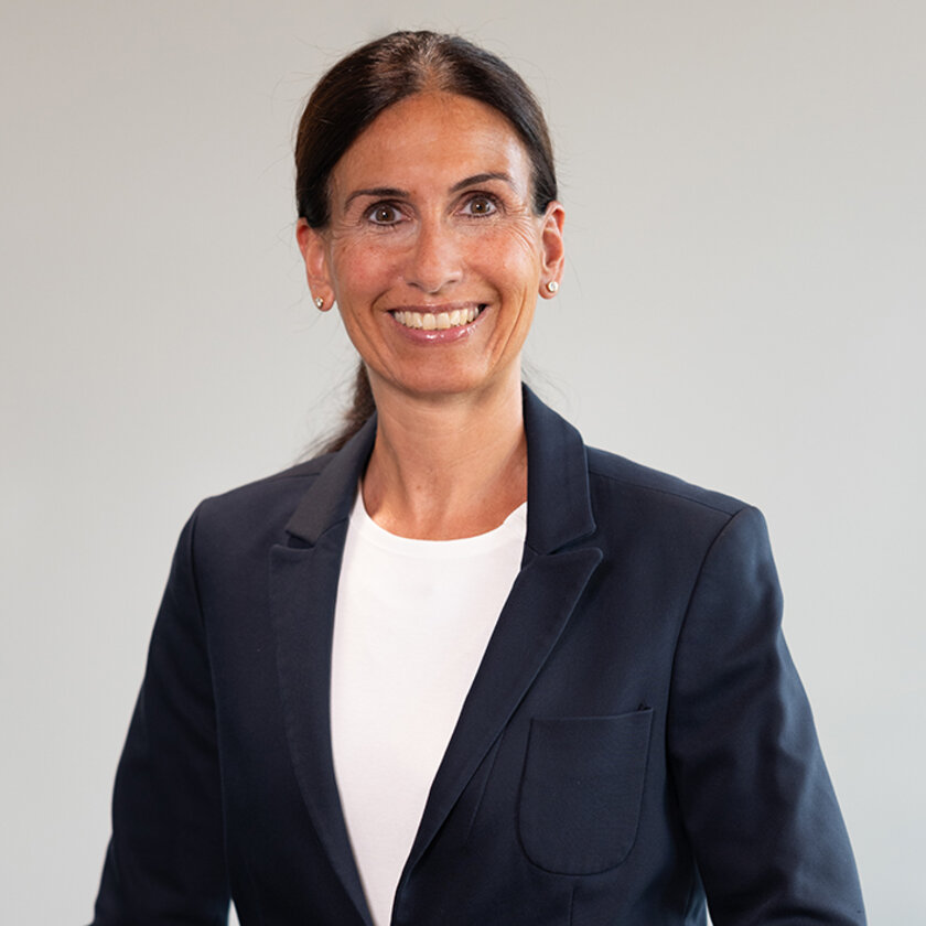 Frau mit dunklen langen Haaren im Anzug und T-Shirt
